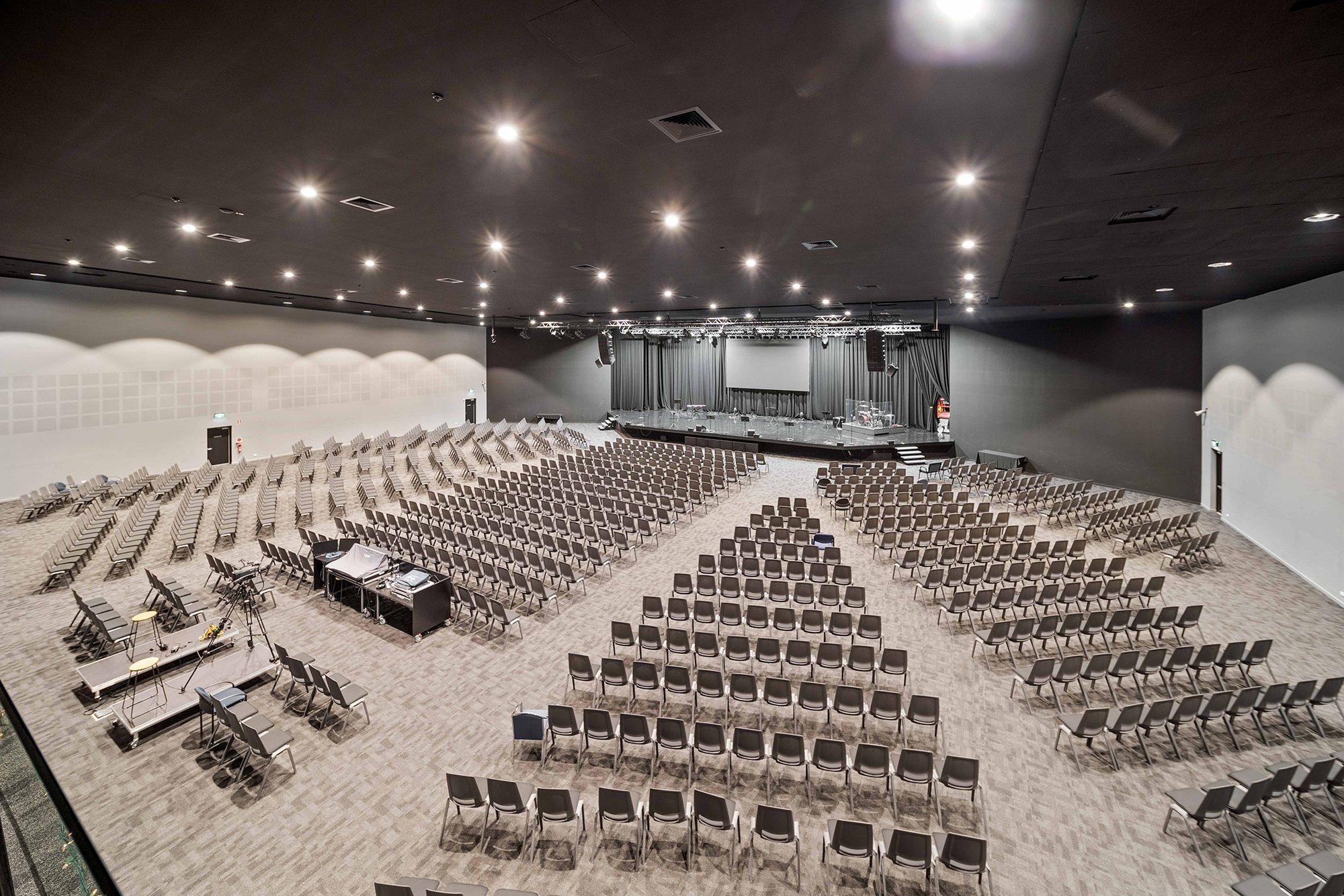 Auditorium with tiered seating, stage lighting and exposed services