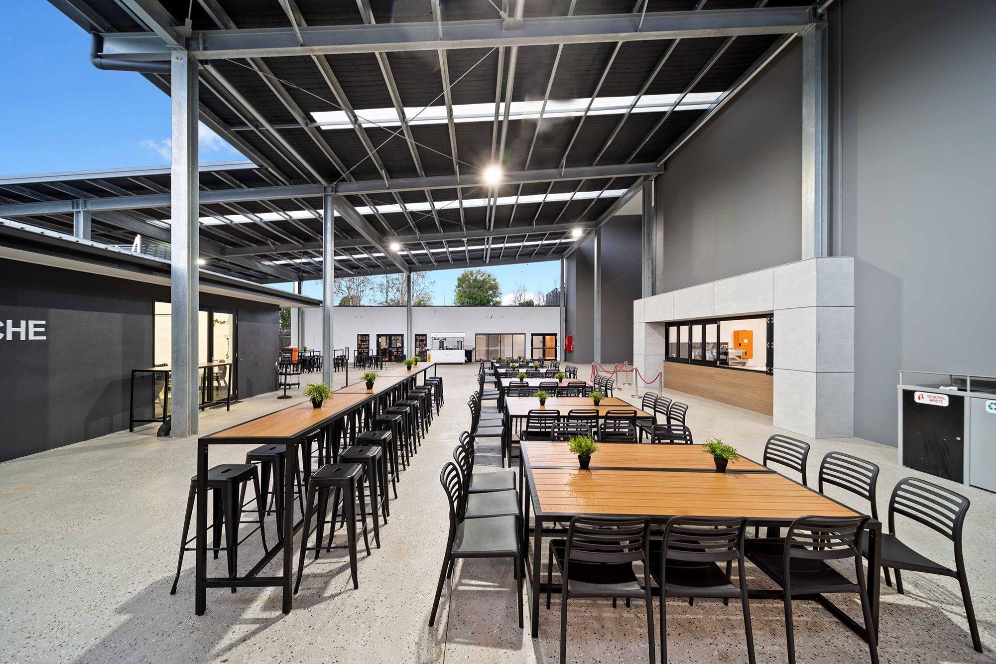 Cafe and gathering space with exposed black ceiling and track lighting