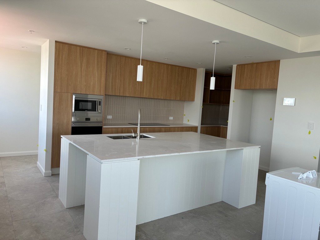 Apartment kitchen with island bench, pendant lights and timber-look joinery