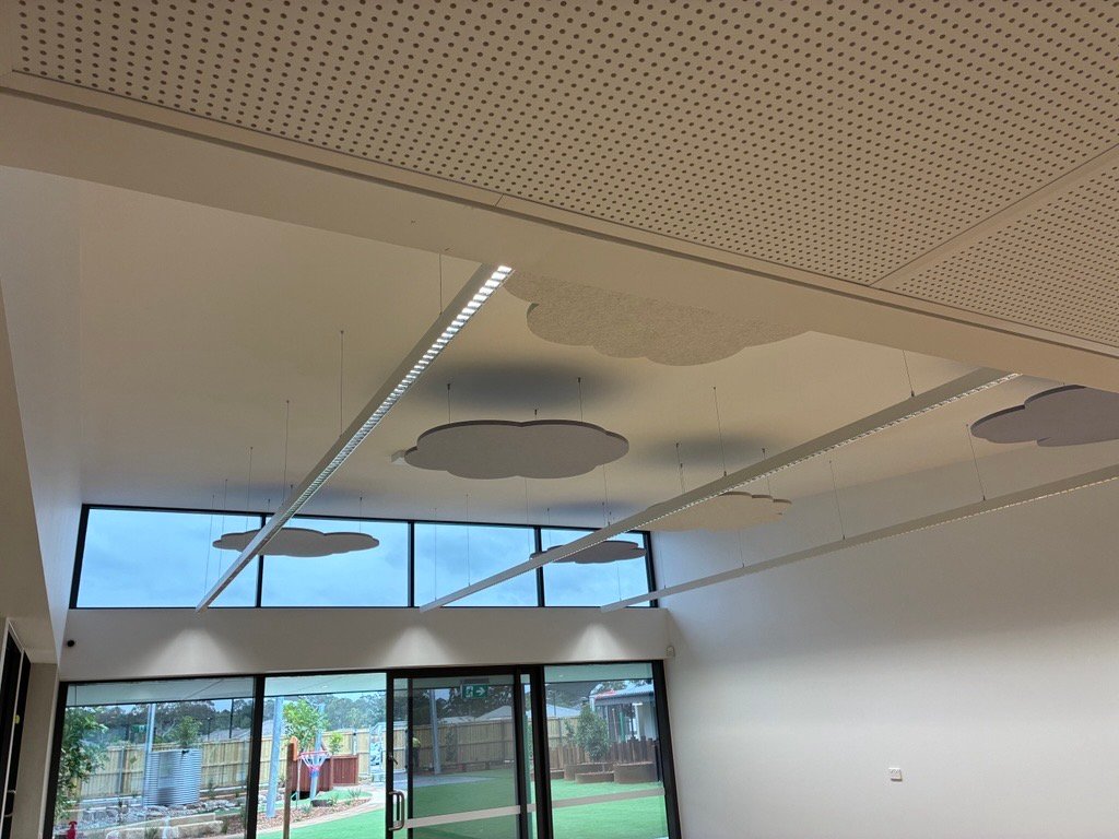Early learning room with linear LED lighting, cloud-shaped acoustic panels and full-height glazing