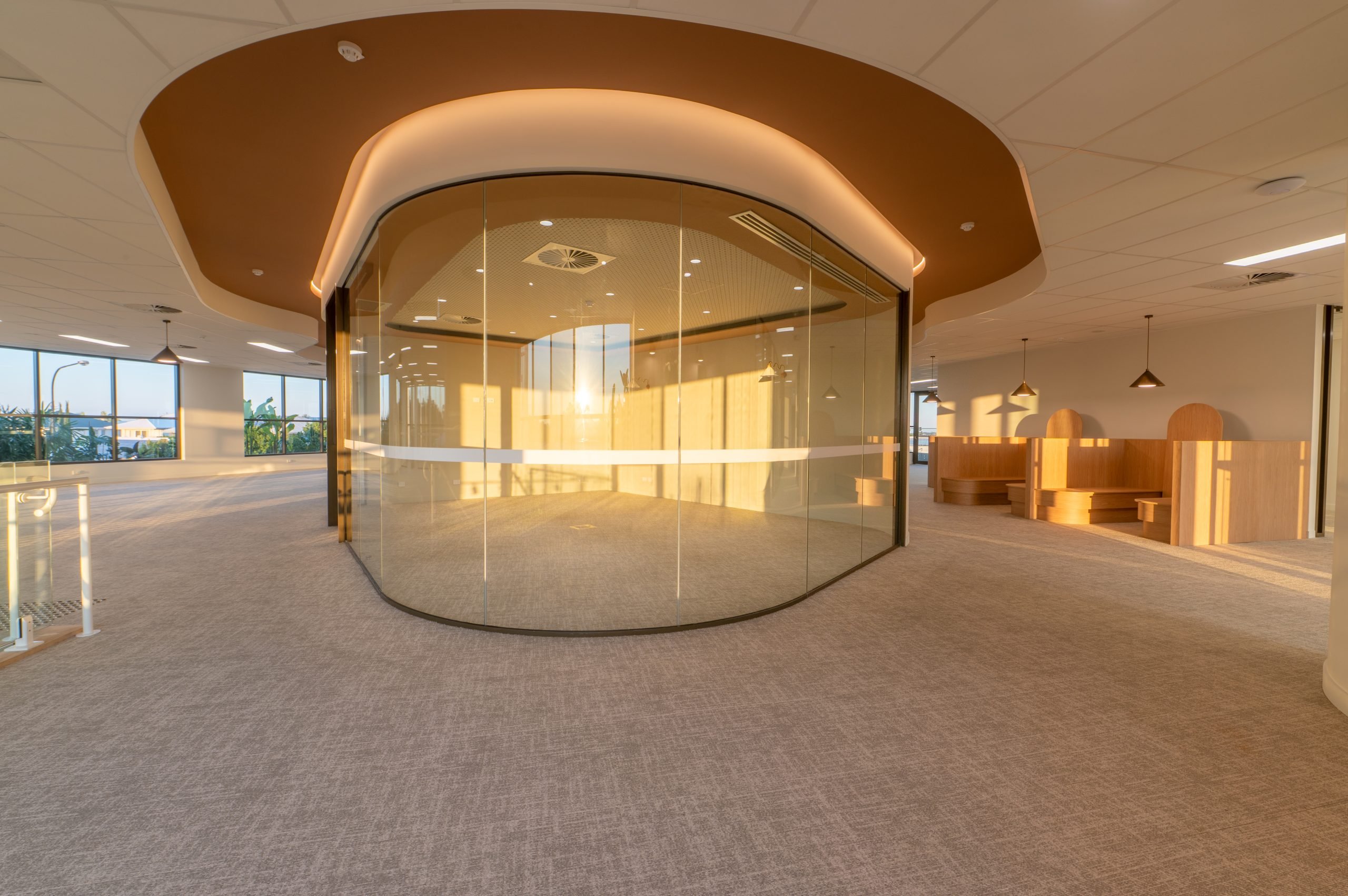 Curved glass meeting room under a sculpted ceiling
