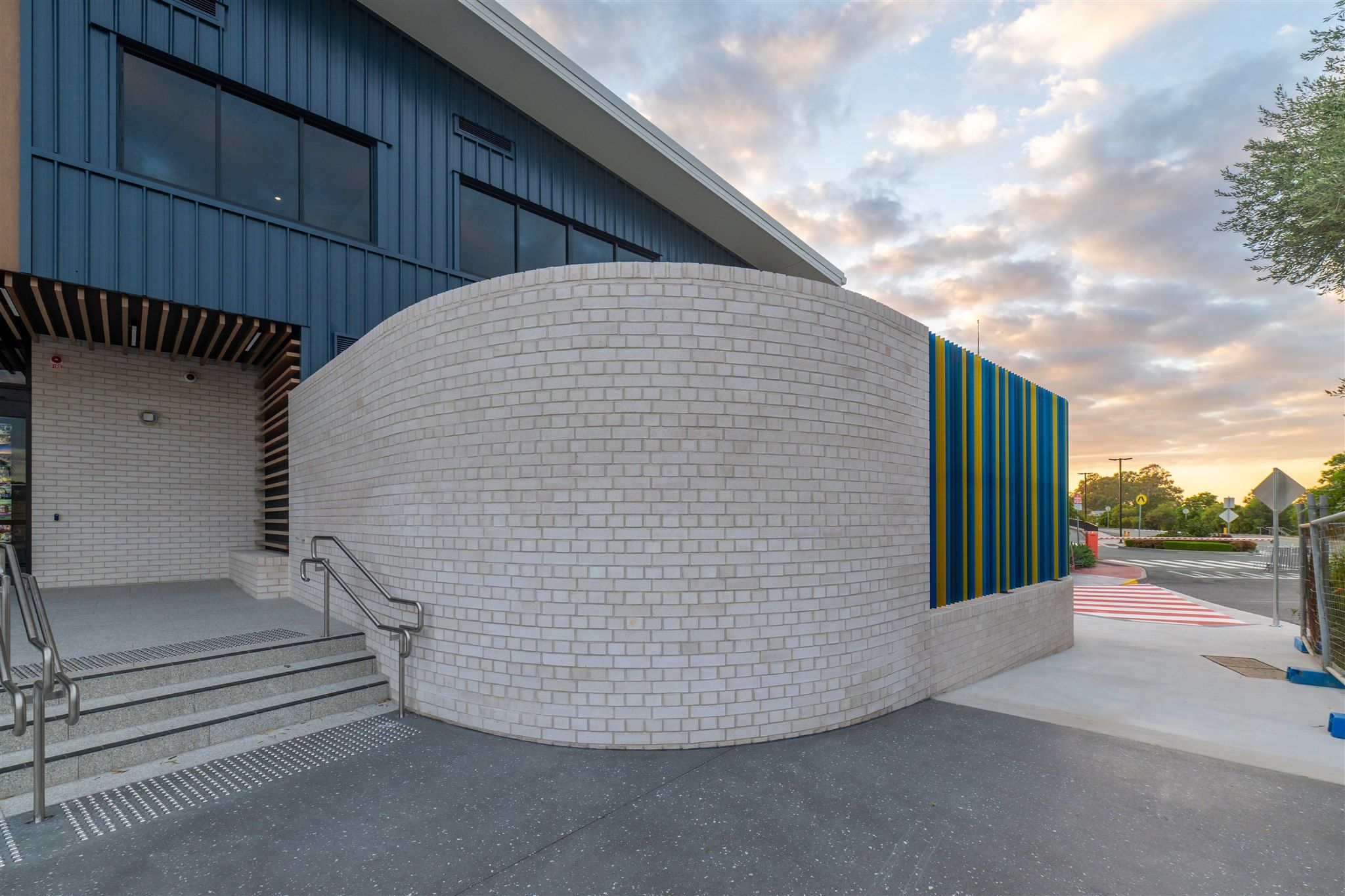 Curved brick facade and timber battens at dusk