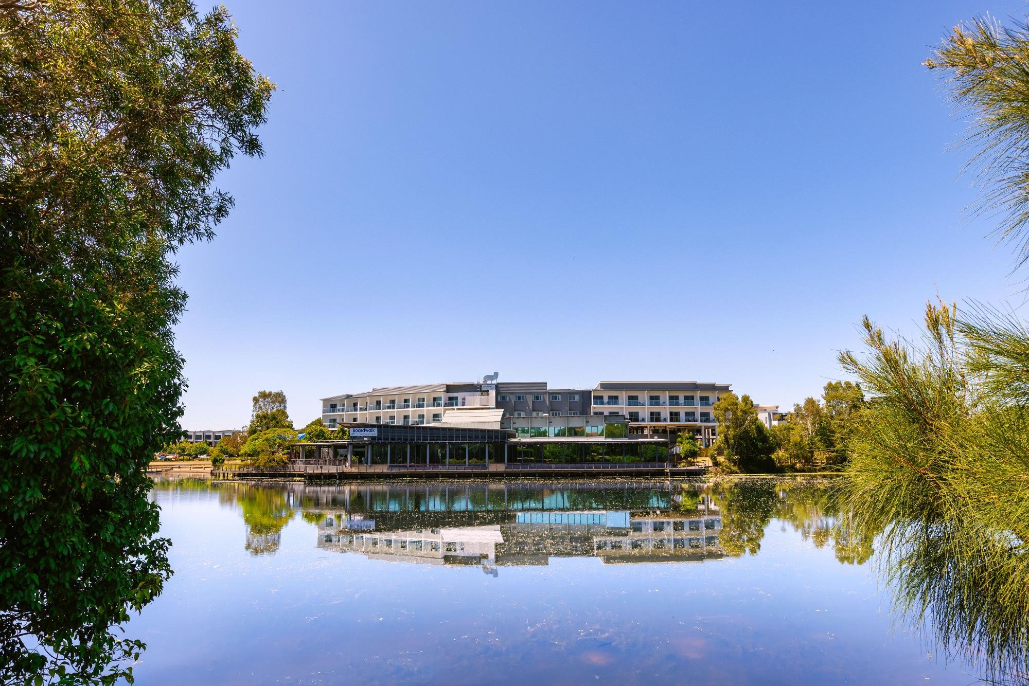 Hotel reflected in still water under blue sky