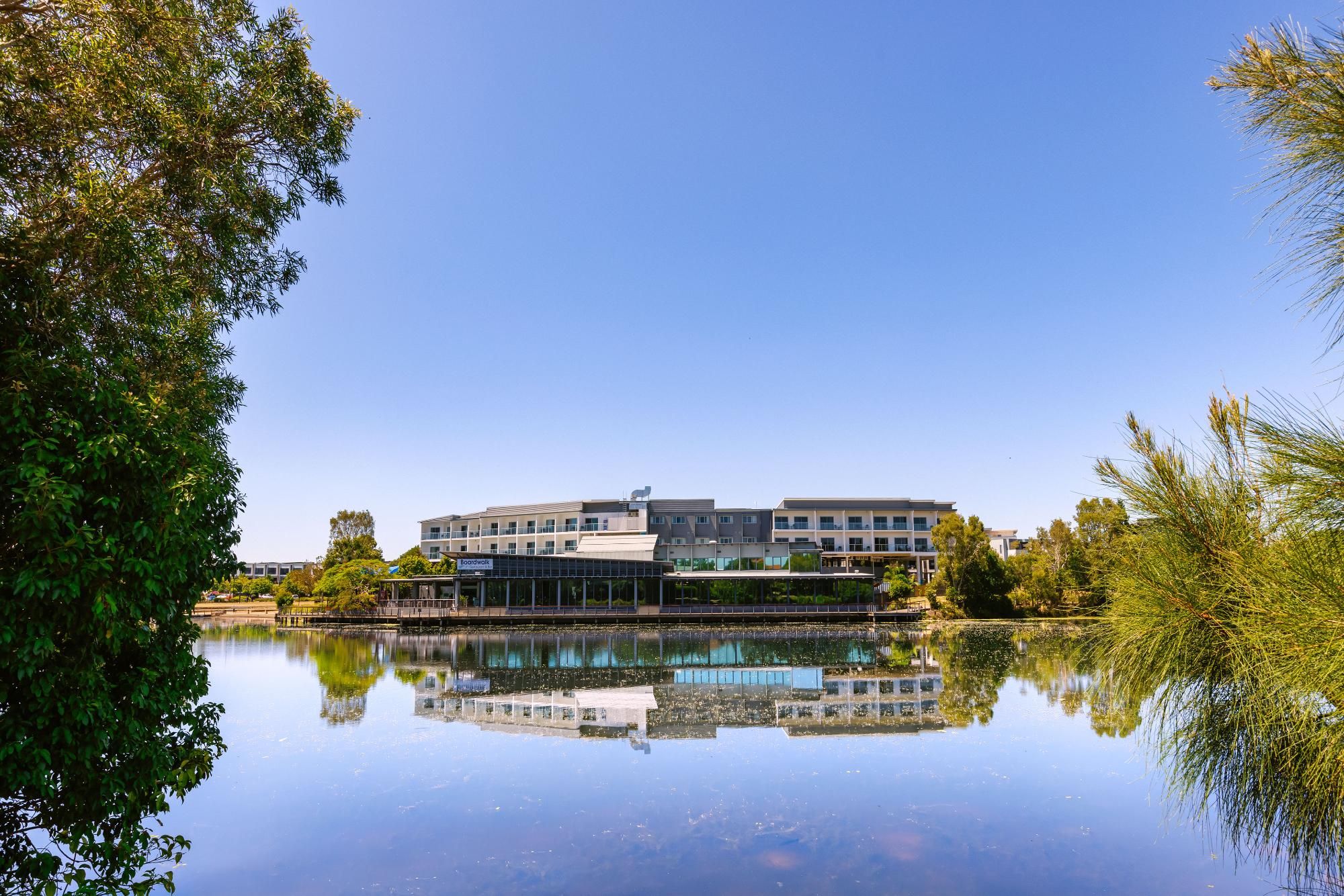 Hotel reflected in still water under blue sky
