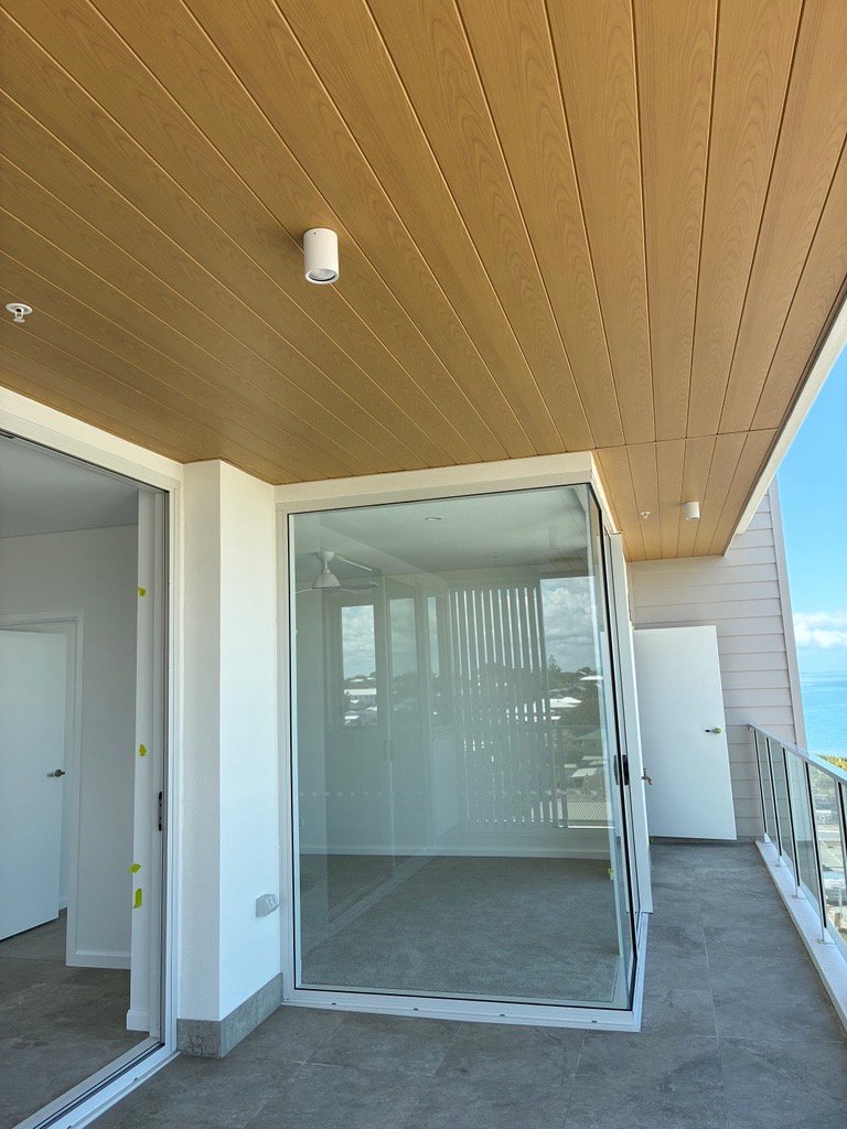 Apartment balcony with timber-look ceiling lining, ceiling light and sliding glass doors