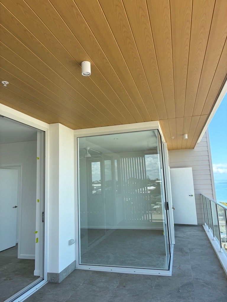 Apartment balcony with timber-look ceiling lining, ceiling light and sliding glass doors