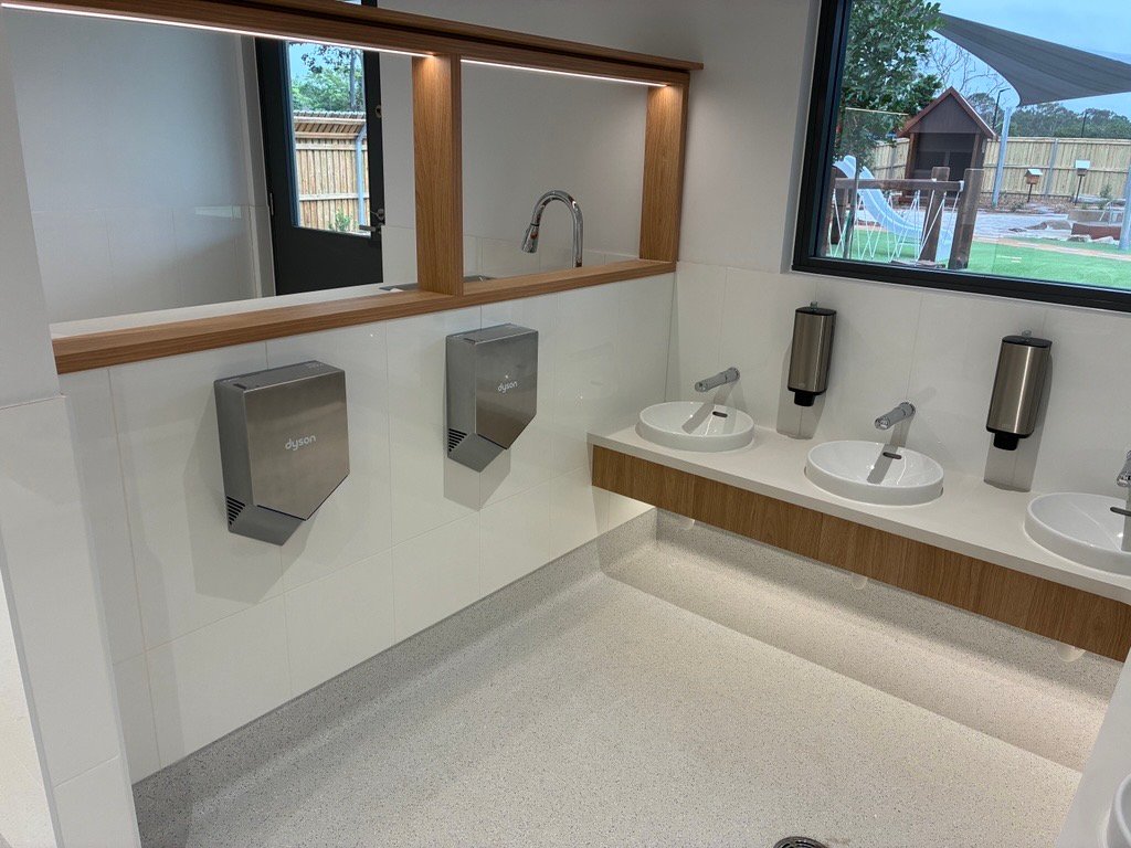 Children's bathroom with low basins, sensor taps and hand dryers