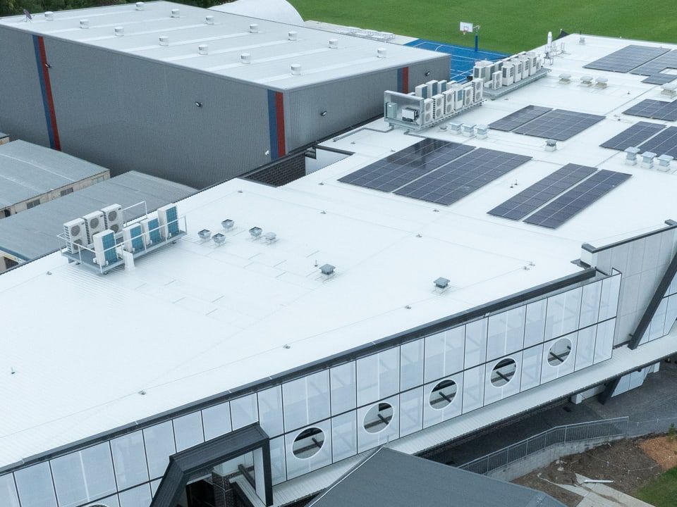 Aerial view of a school building roof with condenser units and solar panels