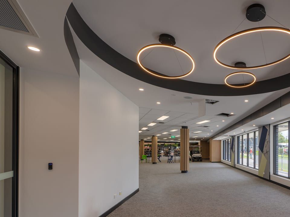 School building corridor with a door access reader beside the entry and feature ring lighting