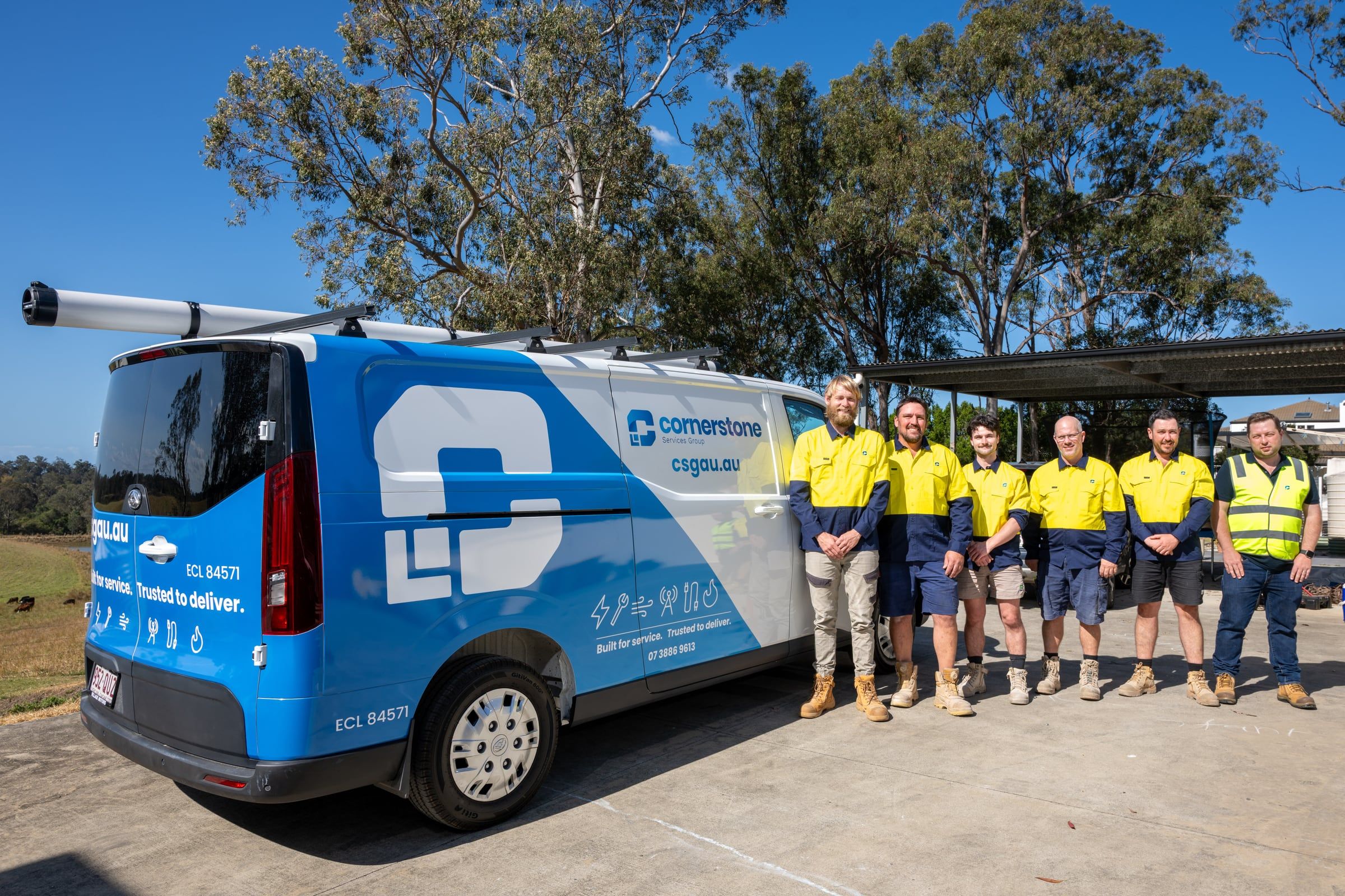 The Cornerstone Services Group team in uniform beside a branded service van